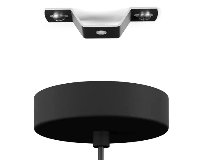 Nærbillede af en mat sort, cylindrisk loftroset med et centralt kabelindgangspunkt. Over den ses et metalbeslag med to skruehuller til sikker montering. Rosetten har en glat overflade og er designet til at skjule elektriske forbindelser for et rent og moderne udseende.