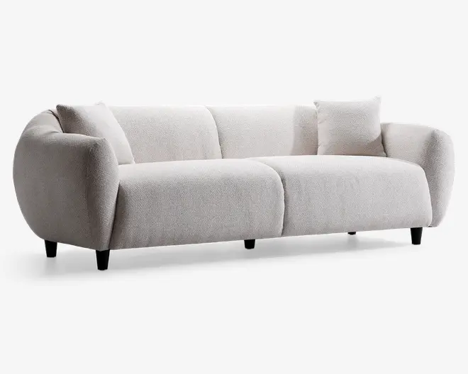 Moderne sofa med blødt, tekstureret lysebeige betræk. Har afrundede, polstrede armlæn og ryglæn, der giver et hyggeligt udtryk. Sædehynderne er tykke og delt i to sektioner. Inkluderer en matchende, firkantet pyntepude. Sofaen står på korte, sorte ben, hvilket giver et let hævet udseende.
