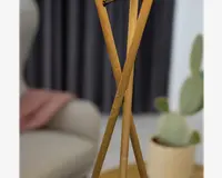 Nærbillede af tre slanke ben i lyst træ, arrangeret i en tripod-formation med en glat, naturlig træstruktur. Benene krydser hinanden elegant og giver et moderne og minimalistisk udtryk. Træet fremstår poleret og robust, velegnet til moderne indretning.