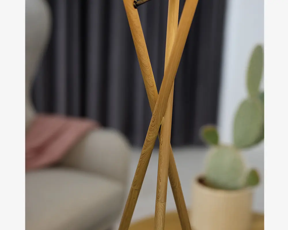 Nærbillede af tre slanke ben i lyst træ, arrangeret i en tripod-formation med en glat, naturlig træstruktur. Benene krydser hinanden elegant og giver et moderne og minimalistisk udtryk. Træet fremstår poleret og robust, velegnet til moderne indretning.