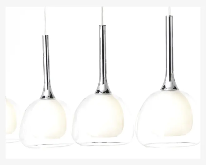 Moderne pendellamper med en blank kromstang og en kuppelformet skærm af klart glas. Inden i glasskærmen er der en mat, hvid indre diffuser, som blødgør lyset. Lamperne hænger i tynde, hvide ledninger og har et stilrent, nutidigt udtryk.