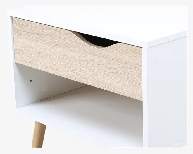 Rektangulært møbel med hvid ramme, en enkelt skuffe i lyst træ med buet udskæring som greb, en åben hylde under skuffen og skråtstillede ben i lyst træ. Designet er minimalistisk og moderne.