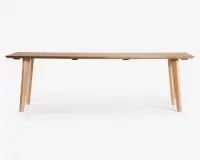 Rektangulær bænk lavet af lyst træ med en glat, flad overflade og fire skråtstillede ben for stabilitet. Designet er minimalistisk og moderne med rene linjer og en naturlig træstruktur.