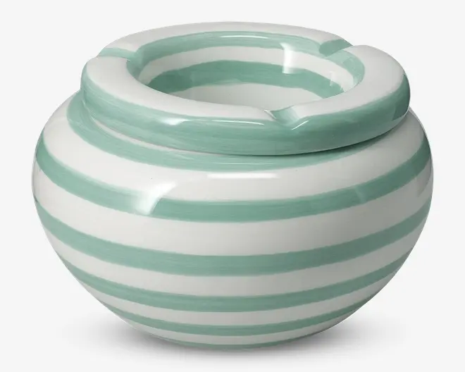 Rund keramisk beholder med en bred, tyk kant og en udskåret åbning. Overfladen har skiftevis vandrette striber i mintgrøn og hvid, hvilket giver et frisk og moderne udtryk. Den blanke finish giver et glat og reflekterende udseende.