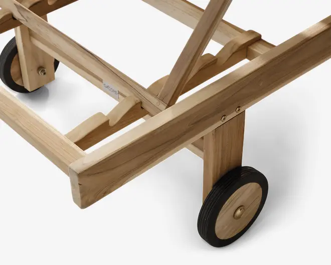 Nærbillede af en træramme med solid konstruktion, der har to sorte gummihjul med træmidte og messingdetaljer. Træet har en naturlig finish, hvor man kan se årerne og strukturen. Rammen har forstærkede samlinger og metalskruer for ekstra stabilitet. Designet indikerer nem mobilitet og holdbarhed.