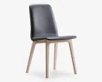 Stol med et slankt, moderne design med sort polstret sæde og ryglæn med diskrete syninger. Benene er lavet af lyst træ og vinklet udad for stabilitet og stil. Ryglænet er let buet for ergonomisk støtte.