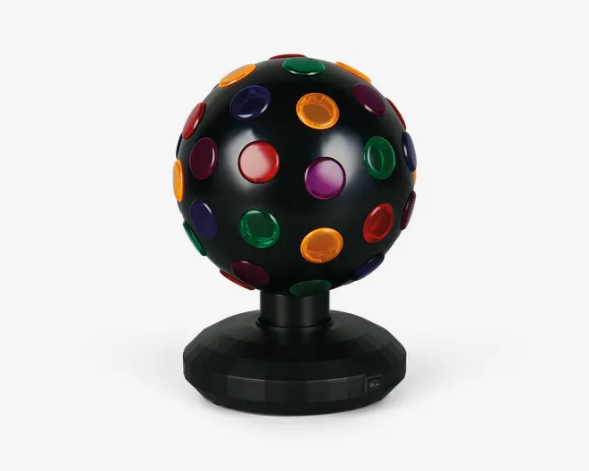 Sort kugleformet enhed med mat overflade, udstyret med flere runde, gennemsigtige linser i rød, grøn, gul, lilla og blå, jævnt fordelt over hele overfladen. Kuglen er monteret på en solid, facetslebet sort fod med en lille tænd/sluk-knap og er designet til at rotere og projicere farverige lys, når den er i brug.