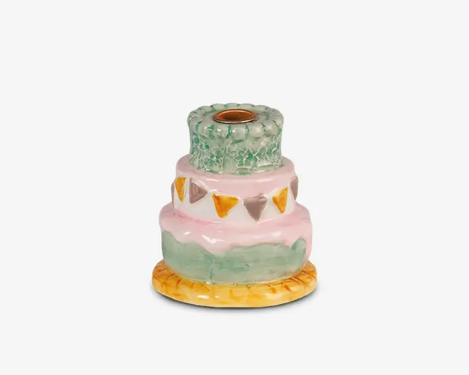 Keramisk lysestage formet som en lagdelt kage med tre etager. Basen er rund og gul, som et kagefad. Nederste lag er grønt med en bølget lyserød kant, midterste lag er lyserødt med malede trekantede flag i gul, orange og grå, og øverste lag er grønt med krakeleret overflade. Lysholderen sidder i midten øverst.