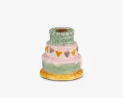 Keramisk lysestage formet som en lagdelt kage med tre etager. Basen er rund og gul, som et kagefad. Nederste lag er grønt med en bølget lyserød kant, midterste lag er lyserødt med malede trekantede flag i gul, orange og grå, og øverste lag er grønt med krakeleret overflade. Lysholderen sidder i midten øverst.