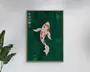 Indrammet vægkunst med en stiliseret koi-fisk med orange, sorte og hvide aftegninger på en dybgrøn baggrund med abstrakte vandringe og diskrete former af vandplanter. Japanske tegn og en lille rød cirkel er placeret lodret i øverste venstre hjørne. Rammen er i lyst træ, og kunstværket har et moderne, minimalistisk udtryk.