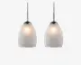 Et sæt pendellamper med matterede glasskærme, der har et diskret indgraveret linjemønster. Skærmene er ovale og udsender et blødt, varmt lys. Hver lampe hænger fra en stilren stang med kromfinish, hvilket giver et moderne og elegant udtryk.