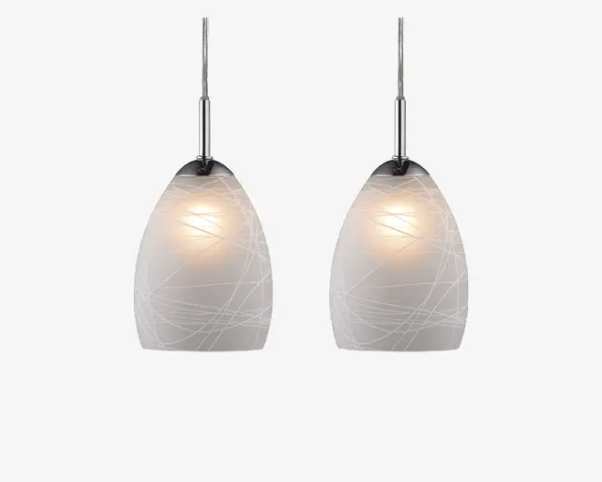 Et sæt pendellamper med matterede glasskærme, der har et diskret indgraveret linjemønster. Skærmene er ovale og udsender et blødt, varmt lys. Hver lampe hænger fra en stilren stang med kromfinish, hvilket giver et moderne og elegant udtryk.