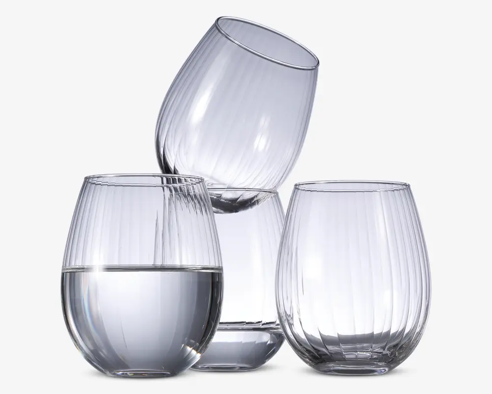 Sæt med tre klare, stilkfri glas med rund form og lodret rillet tekstur. Ét glas er delvist fyldt med vand, mens de to andre er tomme. Glassene har et moderne, elegant design og en solid bund for stabilitet.