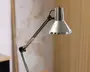Justerbar skrivebordslampe med blank kromfinish, konisk lampeskærm og ledarm med synlige samlinger for fleksibel placering. Lampen har et slankt, moderne design og er velegnet til arbejdsbelysning.