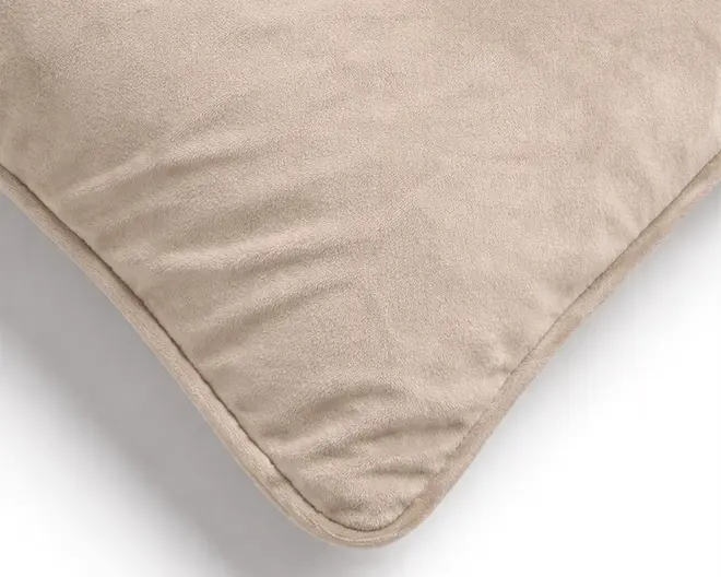 Nærbillede af en beige velourpude med blød, luftig struktur og en pænt kantbåndsafsluttet afrundet hjørne.