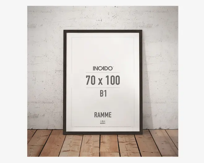 Rektangulær billedramme med en tynd, mørk kant, måler 70 x 100 cm. Rammen har et moderne, minimalistisk design og står op ad en lys, tekstureret væg på et trægulv. Rammen er velegnet til store plakater eller kunstværker.