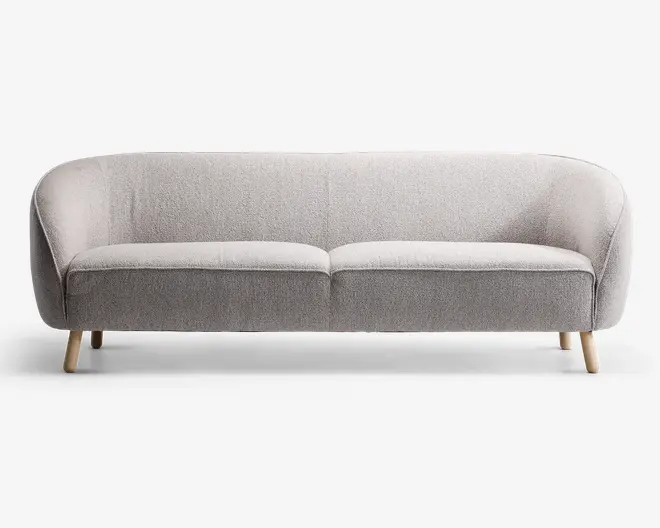 En moderne tresæders sofa med lysegråt, tekstureret stofbetræk. Sofaen har en let buet ryg og armlæn, der giver en hyggelig og omsluttende form. Den har to sædehynder og står på fire korte, skråtstillede træben i naturfarve, hvilket giver et skandinavisk inspireret udtryk.