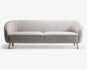 En moderne tresæders sofa med lysegråt, tekstureret stofbetræk. Sofaen har en let buet ryg og armlæn, der giver en hyggelig og omsluttende form. Den har to sædehynder og står på fire korte, skråtstillede træben i naturfarve, hvilket giver et skandinavisk inspireret udtryk.