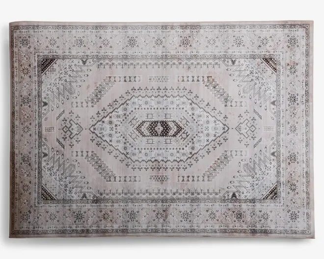 Rektangulært tæppe med et centralt diamantformet mønster og indviklede geometriske detaljer i nuancer af beige, brun og lysegrå. Kanten er dekoreret med små blomster- og abstrakte motiver, og hjørnerne har detaljerede trekantede accenter. Tæppet har et vintage-inspireret udtryk med en let slidt finish, der giver et blødt og afdæmpet udseende.