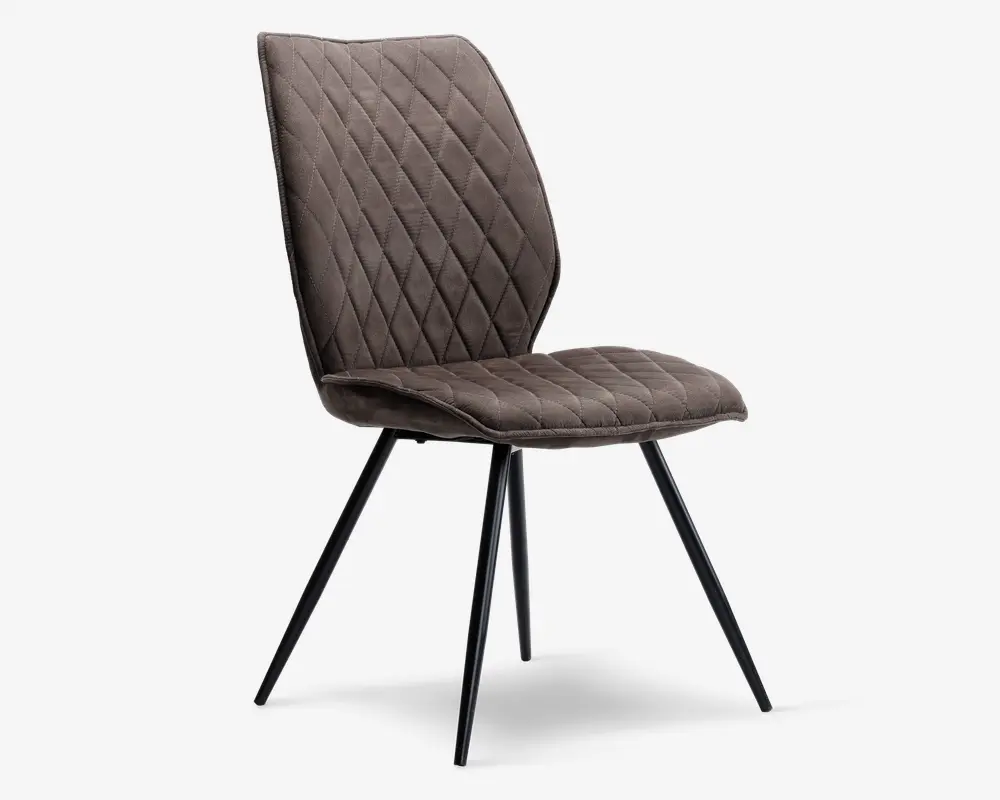 Stol med polstret sæde og ryglæn betrukket med et blødt, brunt stof med diamantformet quiltet mønster. Ryglænet er let vinklet for ergonomisk støtte. Stolen står på fire slanke, sorte metalben, der er skråt udad for stabilitet og et moderne udtryk.