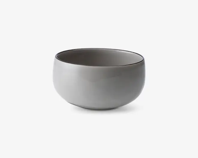 En rund, glat keramikskål med mat lysegrå yderside og en lidt mørkere inderside. Skålen har et minimalistisk design med blødt buede sider og en bred åbning, velegnet til servering af supper, salater eller snacks.