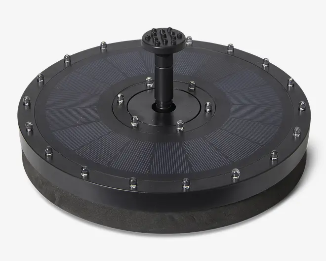 Rund, sort enhed med en flad, segmenteret overflade, der ligner solpaneler, omgivet af jævnt fordelte metalbolte. I midten er der en hævet cylindrisk dyse med flere små huller på toppen, sandsynligvis til vandstråle. Basen er tyk og ser ud til at være lavet af skum eller et lignende materiale for opdrift.