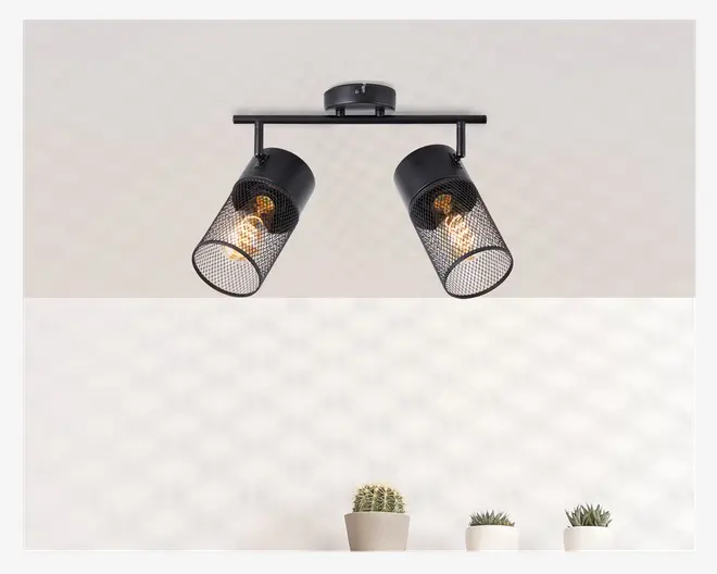 Loftmonteret lampe med to justerbare cylindriske lampeskærme, hver med et sort metalnet. Pærerne er synlige gennem nettet, hvilket giver et industrielt og moderne udtryk. Lampen er fastgjort til en rund base og en vandret stang, så lampeskærmene kan vinkles i forskellige retninger.