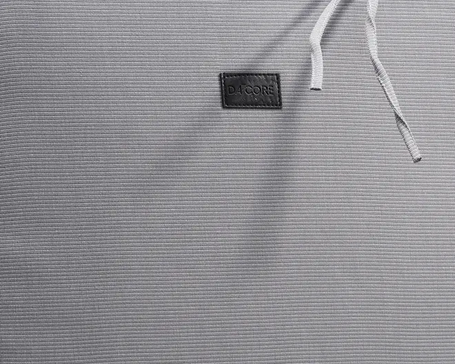 Nærbillede af et lysegråt, fint tekstureret stof med diskrete horisontale linjer. Der er et lille, rektangulært sort mærke med mærkenavnet 'D4CORE' syet på stoffet. En hvid snor er delvist synlig øverst til højre, hvilket antyder, at varen muligvis har en justerbar talje eller lukning.