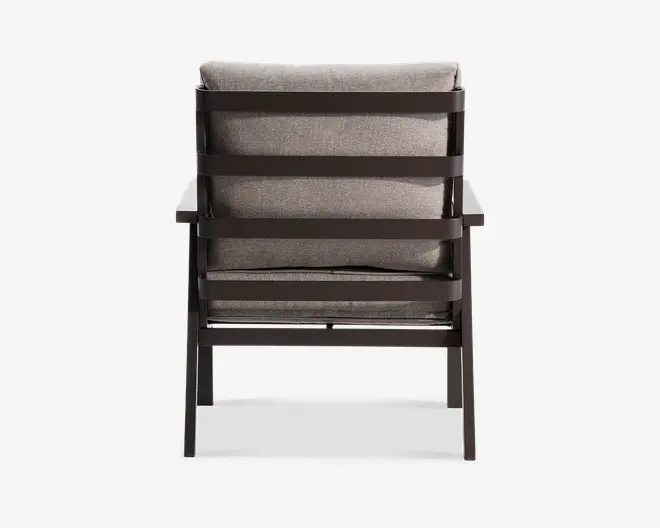 Bagsiden af en stol med en solid, mørk metalramme og vandrette lameller på ryggen. Stolen har tykke, lysegrå hynder på både sæde og ryg, hvilket giver komfort og støtte. Armlænene er brede og flade og matcher rammens finish.