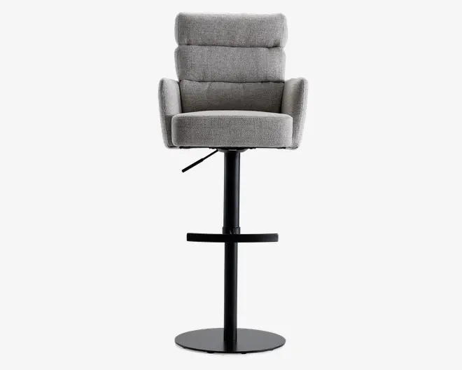 En moderne barstol med polstret sæde, ryglæn og armlæn betrukket med lysegråt stof. Ryglænet har vandrette syninger for ekstra komfort og stil. Stolen har en sort metalbase med cirkulær fodstøtte og rund sokkel, samt en håndtag til justerbar højde.