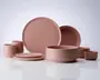 Et sæt mat, støvet rosa keramikservice med et minimalistisk design. Sættet indeholder store og små tallerkener, skåle i forskellige størrelser og kopper. Alle dele har glatte, ensfarvede overflader med blødt afrundede kanter, hvilket giver et moderne og elegant udtryk.