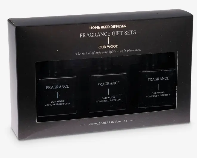 Elegant sort gaveæske med tre firkantede glasflasker, hver mærket "Oud Wood Home Reed Diffuser." Emballagen har guld- og hvid tekst, der fremhæver det som et duft-gavesæt. Hver flaske indeholder 30 ml (1,02 fl. oz) produkt. Æsken har et klart vindue, der viser flaskerne indeni, og det samlede design er stilrent og moderne, velegnet som gave.