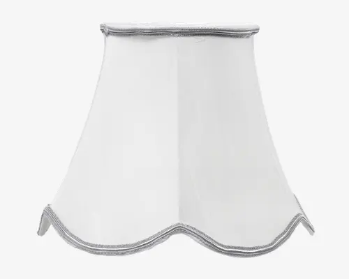 Hvid lampeskærm med en klokkeformet, udvidet design og blødt bølget kant nederst. Der er sølvfarvet kantbånd langs både top og bund, hvilket giver et diskret dekorativt præg. Stoffet er glat og let gennemsigtigt, så lyset spredes blødt.