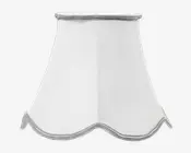 Hvid lampeskærm med en klokkeformet, udvidet design og blødt bølget kant nederst. Der er sølvfarvet kantbånd langs både top og bund, hvilket giver et diskret dekorativt præg. Stoffet er glat og let gennemsigtigt, så lyset spredes blødt.