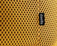 Nærbillede af et sennepsgult stof med en åndbar, bikube-lignende meshstruktur. Stoffet har et lille sort mærke med mærkenavnet 'daells' i hvid tekst. Syningen er synlig og viser en solid samling.