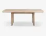 Rektangulært bord med lys træfinish, blødt afrundede hjørner og tykke, flade panelben i hver ende. Designet er minimalistisk og moderne med en glat bordplade og synlig træstruktur.