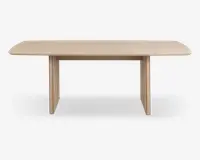 Rektangulært bord med lys træfinish, blødt afrundede hjørner og tykke, flade panelben i hver ende. Designet er minimalistisk og moderne med en glat bordplade og synlig træstruktur.