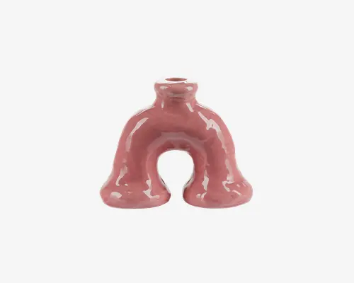 Blank keramikvase med en unik bueform og to afrundede ben samt en lille åbning i toppen til blomster. Vasens overflade er glat og reflekterende, og den har en afdæmpet rosa farve.