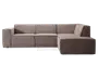 Moderne L-formet sofa med chaiselong til højre. Polstret i et blødt, taupefarvet stof med en diskret tekstur. Har brede, blokformede armlæn på venstre side og rene, lige linjer for et minimalistisk udtryk. Ryglæn og sædehynder er faste og integreret i rammen, hvilket giver et struktureret og moderne look. Sofaen står lavt uden synlige ben.