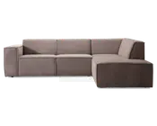 Moderne L-formet sofa med chaiselong til højre. Polstret i et blødt, taupefarvet stof med en diskret tekstur. Har brede, blokformede armlæn på venstre side og rene, lige linjer for et minimalistisk udtryk. Ryglæn og sædehynder er faste og integreret i rammen, hvilket giver et struktureret og moderne look. Sofaen står lavt uden synlige ben.