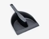 Et sort fejebakke- og kostesæt lavet af holdbar plast. Fejebakken har en bred, buet kant for nem opsamling af snavs og en flad forkant, der sikrer tæt kontakt med gulvet. Kosten har stive sorte børster og et ergonomisk håndtag for komfortabelt greb og effektiv fejning. Begge dele er designet til at passe sammen for praktisk opbevaring.