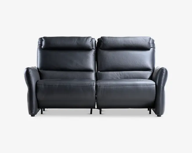 En moderne to-personers sofa betrukket med glat sort læder. Sofaen har bløde, polstrede ryglæn og sædehynder for ekstra komfort. Armlænene er let buede og polstrede, hvilket giver ekstra støtte. Sofaen har et enkelt, minimalistisk design med synlige syninger langs kanterne, hvilket giver et moderne udtryk. Basen er lav, og den samlede konstruktion fremstår solid og velpolstret.