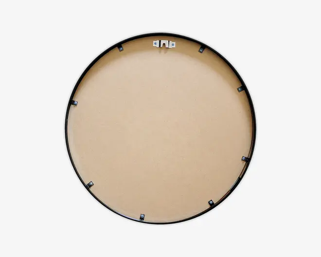 Billedet viser bagsiden af en rund genstand med en glat, lysebrun overflade, sandsynligvis lavet af MDF eller lignende materiale. Den har en sort, cirkulær ramme og flere små sorte klips jævnt fordelt langs kanten, som holder bagbeklædningen fast. Øverst er der et metalophæng til vægmontering.