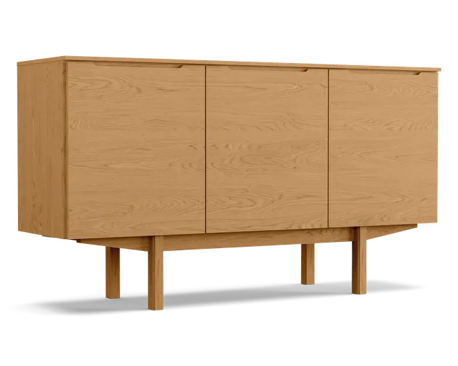 Rektangulært skab i træ med naturlig egetræsfinish, udstyret med tre flade låger med diskrete, integrerede greb øverst. Skabet står på fire solide, firkantede ben, der er forbundet af en vandret støttebjælke, hvilket giver et hævet og stabilt udtryk. Træets årer er synlige på alle flader og tilfører struktur og varme til det minimalistiske design.