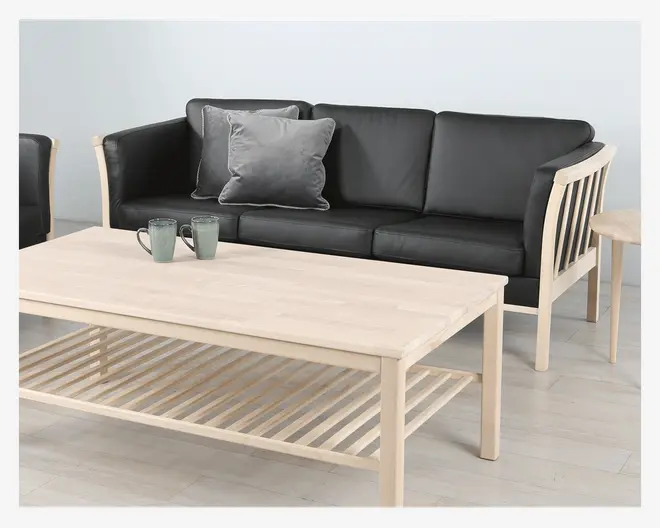 Rektangulært sofabord i lyst træ med en glat bordplade og en underliggende hylde med tremmer til opbevaring. Bordet har lige ben og et minimalistisk design, der passer til en moderne stue. Der står to keramikkrus på bordpladen.