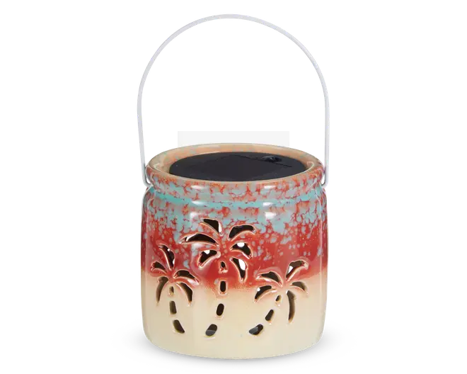 Keramisk lanterne med farveovergang fra creme i bunden til rød og blåplettet foroven. Har udskårne palmetræ-motiver rundt om siderne, så lyset kan skinne igennem. Udstyret med et metalhåndtag til ophængning og et solcellepanel på toppen til opladning.