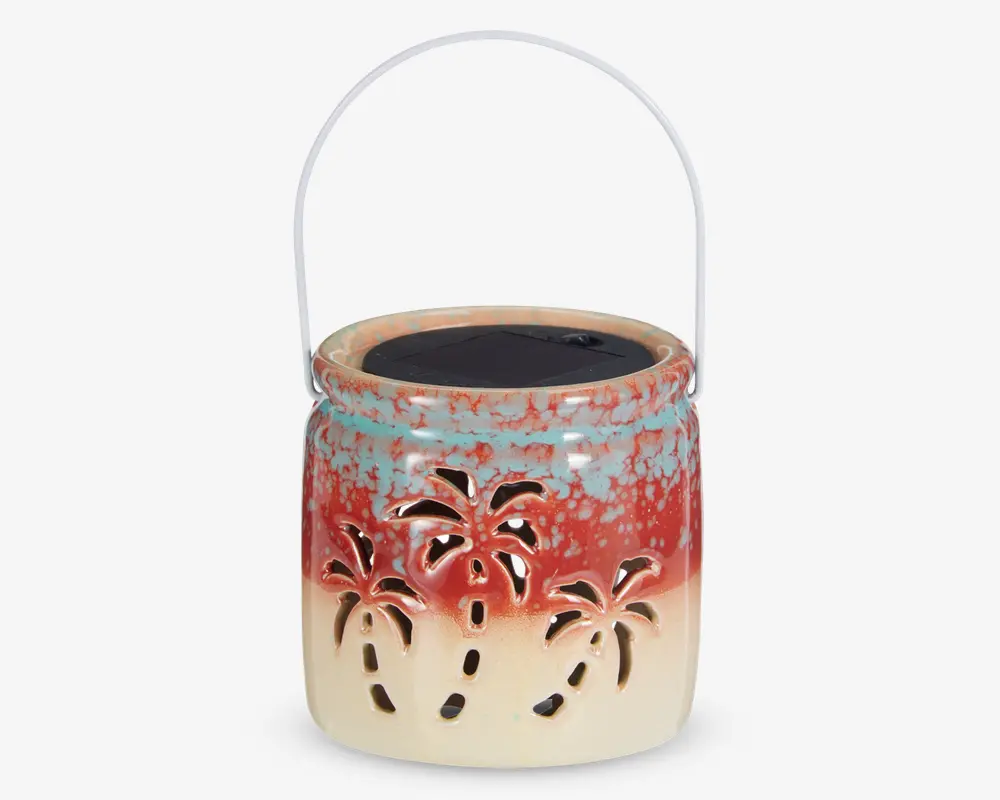 Keramisk lanterne med farveovergang fra creme i bunden til rød og blåplettet foroven. Har udskårne palmetræ-motiver rundt om siderne, så lyset kan skinne igennem. Udstyret med et metalhåndtag til ophængning og et solcellepanel på toppen til opladning.