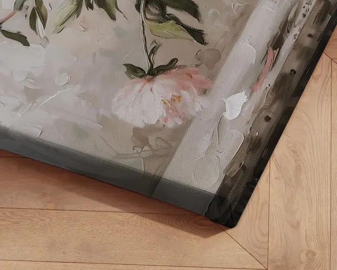Nærbillede af et opspændt lærred med et tekstureret, håndmalet blomsterdesign. Maleriet har synlige penselstrøg og spartelstrøg, med bløde pastelfarver som lyserød, grøn og hvid. Lærredet er stramt spændt omkring en træramme, og hjørnet er pænt afsluttet. Baggrunden viser et lyst trægulv med sildebensmønster.