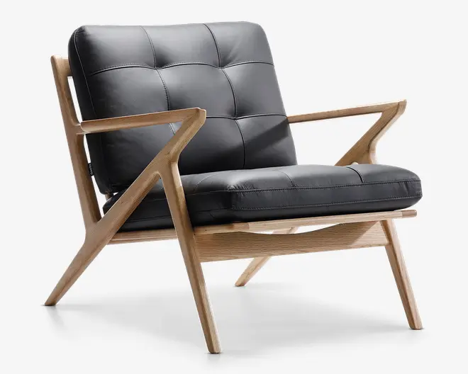Stol med moderne design, let træramme og vinklede, geometriske armlæn og ben. Sæde og ryglæn er polstret med sort læder og har et kvadreret, tuftet mønster, der giver både komfort og stil. Hynderne er tykke og bløde, og trærammen har en naturlig finish, der fremhæver træets åre.