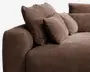 Nærbillede af et sofahjørne betrukket med tekstureret brunt stof. Sofaen har brede, bløde armlæn og leveres med flere store, fyldige ryg- og sidepuder for ekstra komfort og støtte. Stoffet har et blødt, vævet udseende, og designet er moderne og indbydende.
